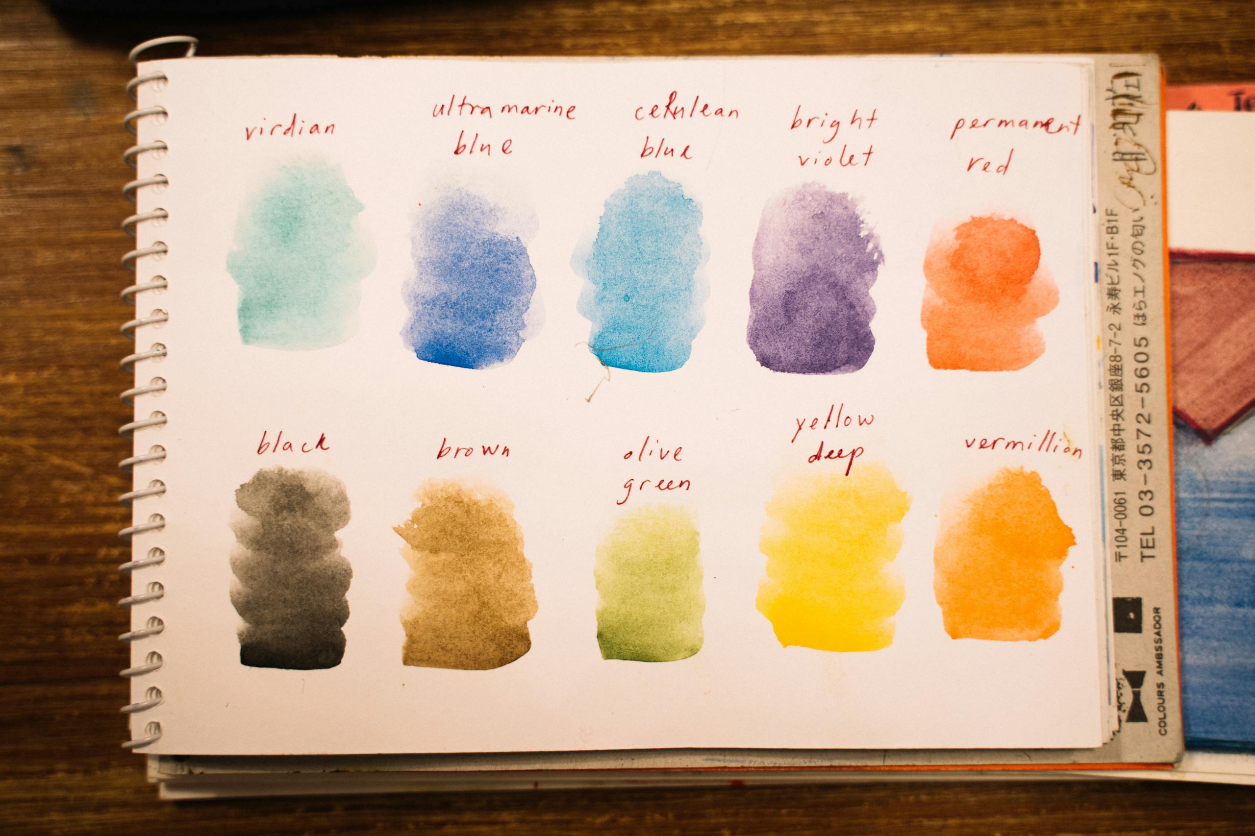 Colorful watercolor palette on notepad showing different shades for artistic choices.